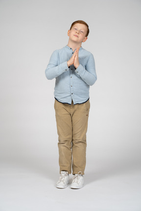 祈りのジェスチャーをしているかわいい男の子の正面図