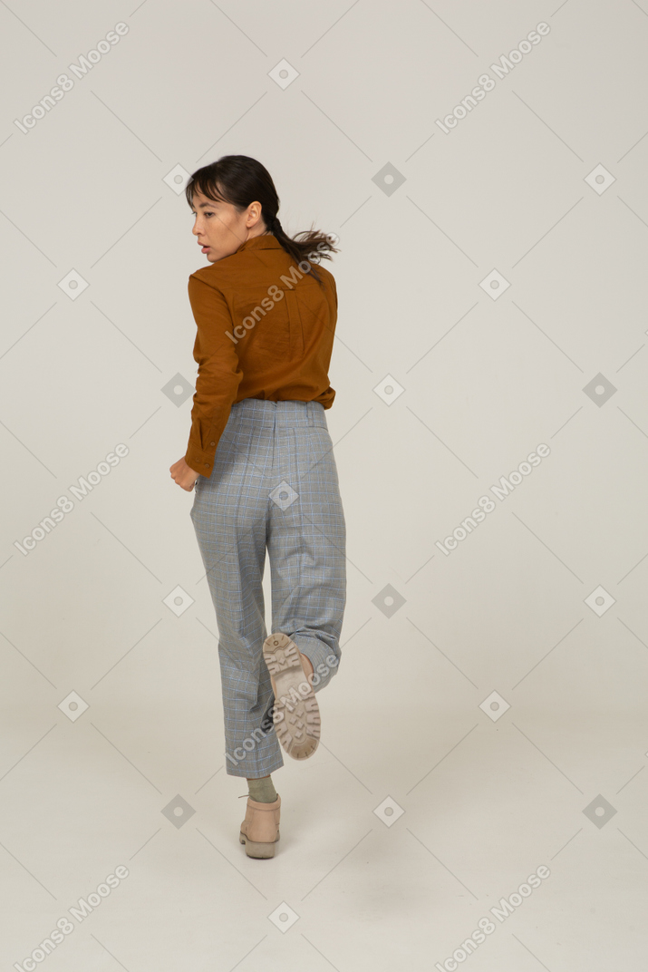 Vista traseira de uma jovem mulher asiática correndo de calça e blusa