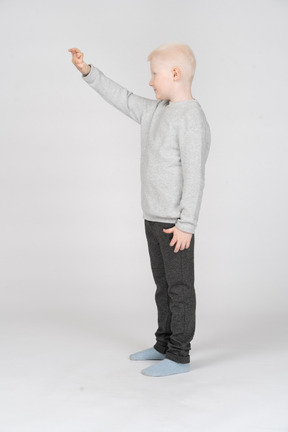 Side view of a boy in casual clothes raising his hand