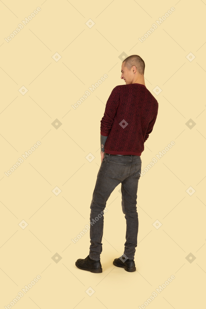 Vista traseira de um jovem fazendo caretas em um suéter vermelho juntando as mãos