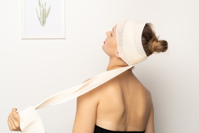 Back view of a young woman removing head bandage