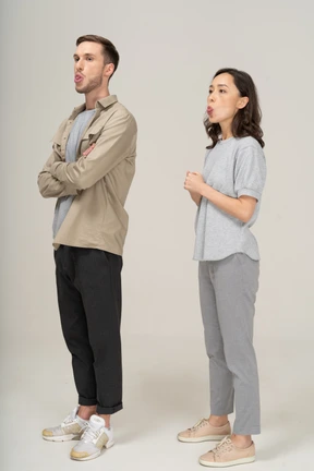 Three-quarter view of young couple showing tongue