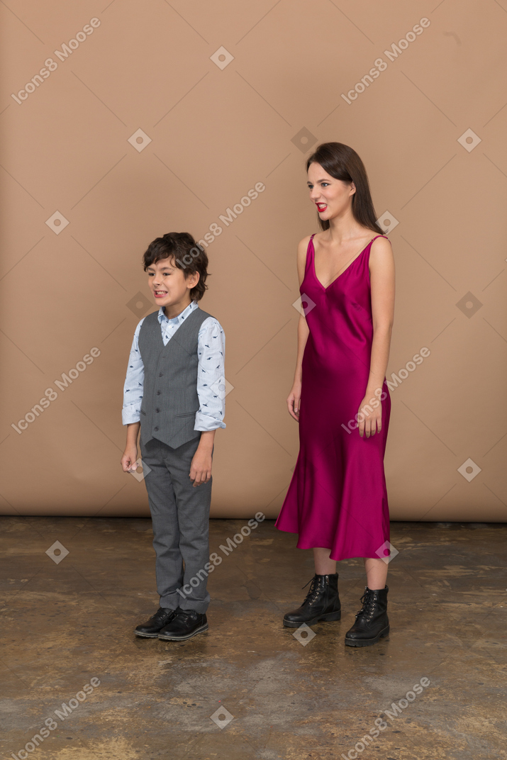 Vista lateral de uma jovem com um vestido vermelho e um menino
