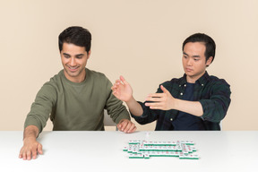 Interracial friends sitting at the table and playing board game