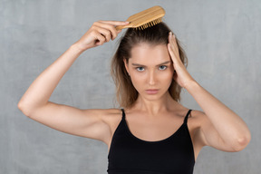 Front view of a young woman brushing her hair