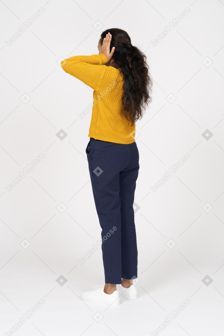 Rear view of a girl in casual clothes covering ears with hands