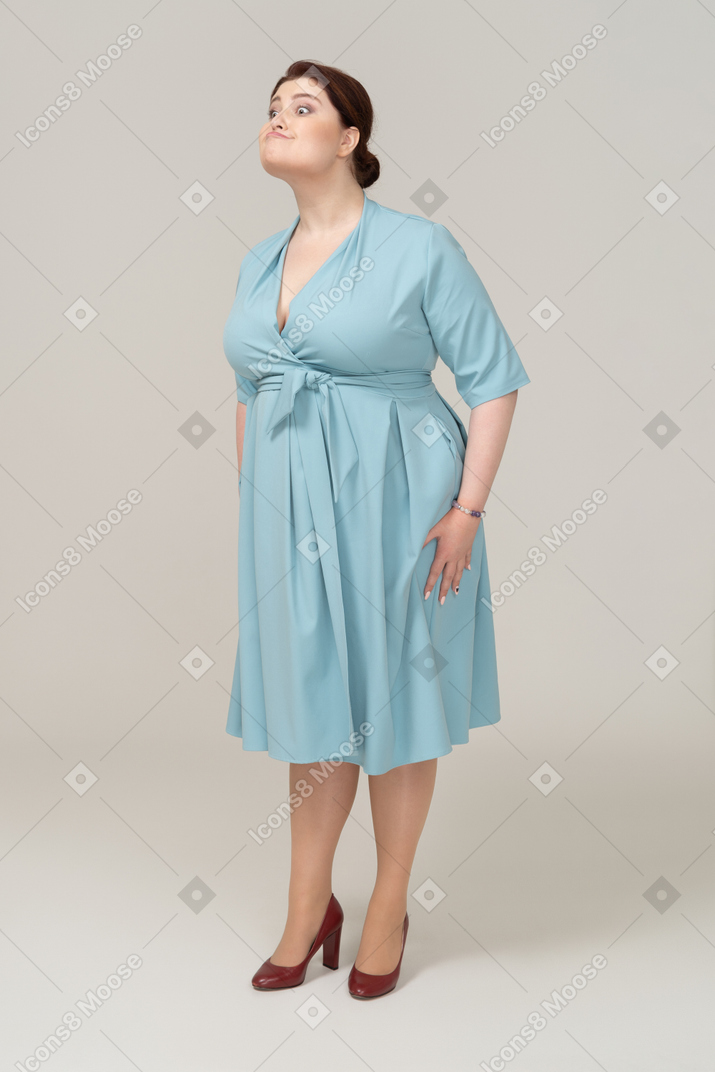 Вид спереди женщины в синем платье корчит рожи