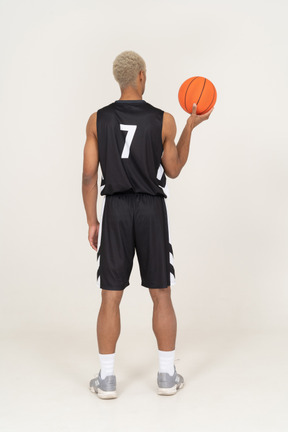 Rückansicht eines jungen männlichen basketballspielers, der einen ball hält