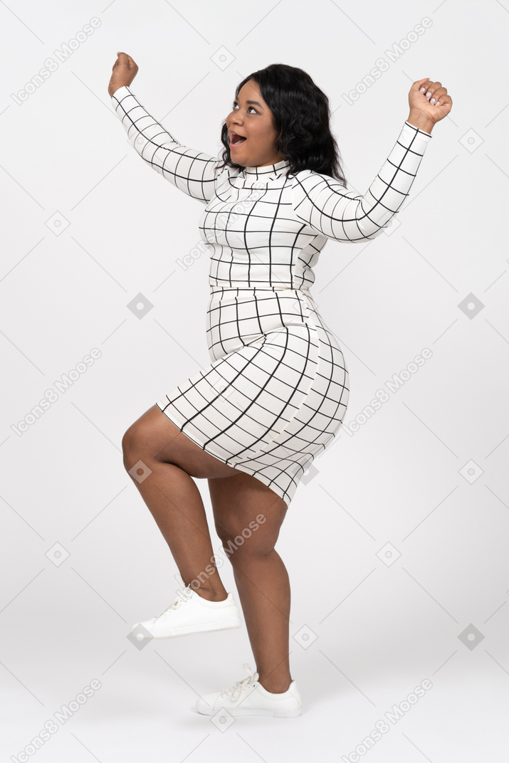 Side view of a happy young woman in casual clothes dancing