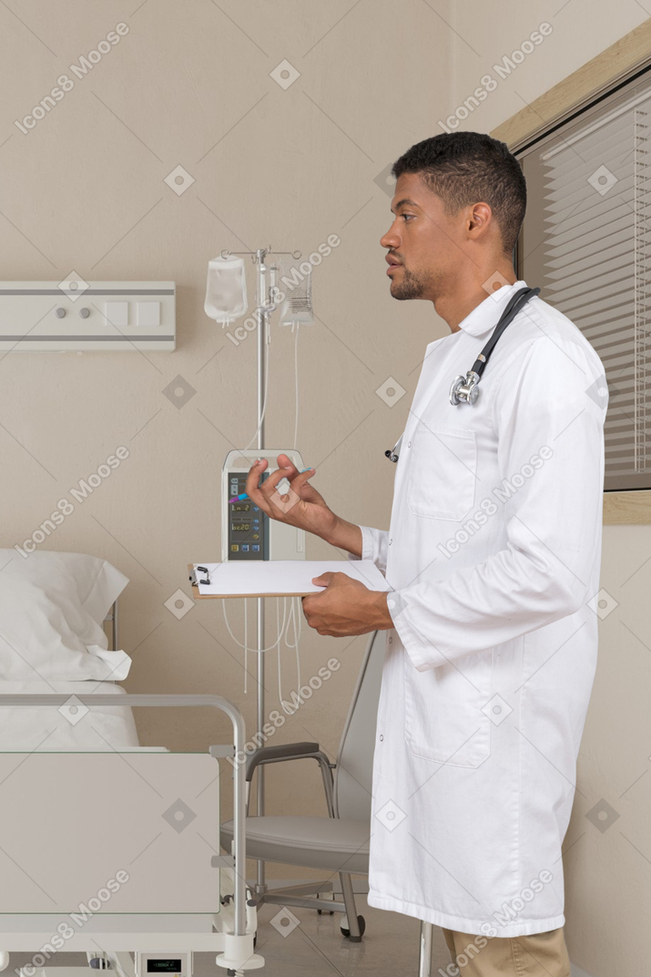 A man in a white lab coat standing next to a hospital bed