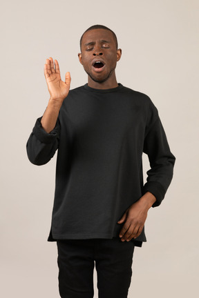 Young man yawning with raised hand