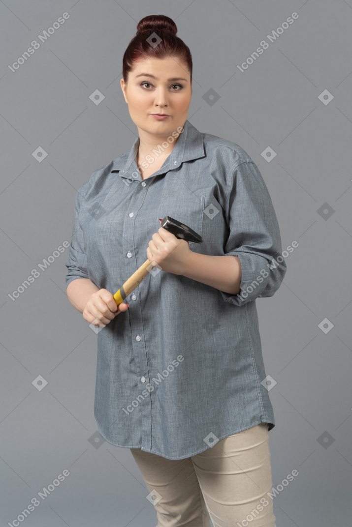Young woman standing with hammer in hands