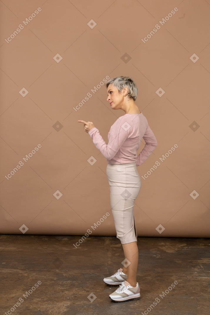 Side view of a woman in casual clothes pointing with finger