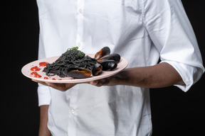 Close-up chef holding seafood pasta