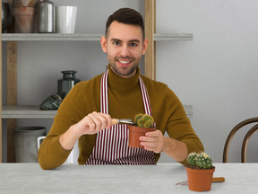 A man in an apron planting a cactus