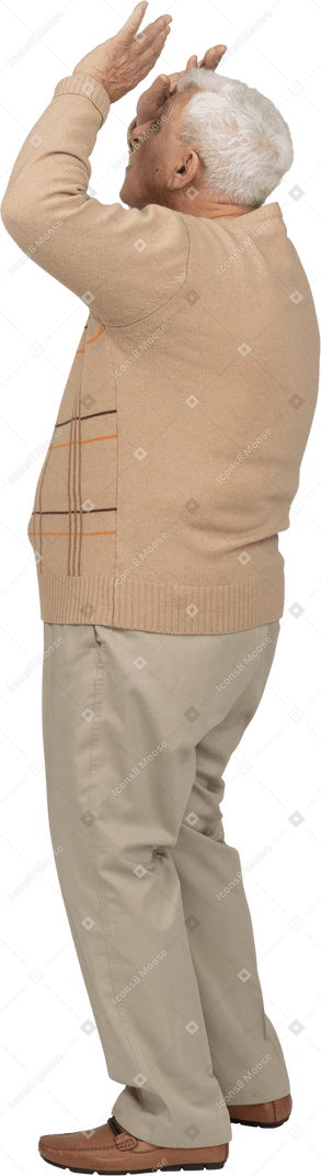 Side view of an old man in casual clothes standing with raised arms
