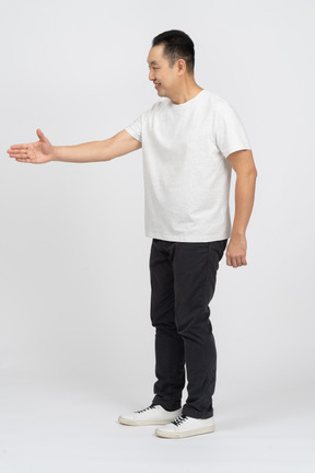 Vista lateral de um homem feliz em roupas casuais, dando uma mão para apertar