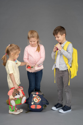 Cheerful little girl sharing toys with friends
