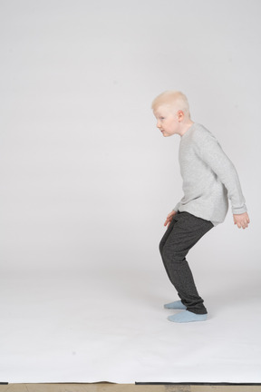 Side view of a boy crouching slightly before the jump