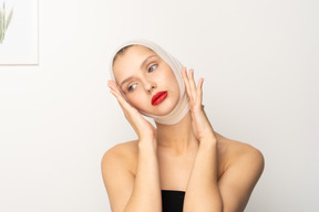 Young woman with bandaged head touching her face