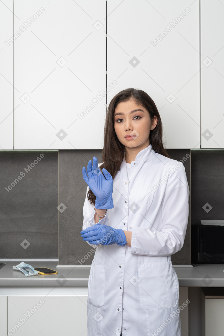 Front view of a female doctor wearing protective gloves and looking at camera