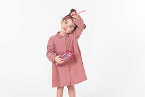 Petite fille enfant tenant une paille et une tasse en plastique rose