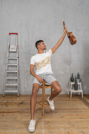 Front view of a man holding an ukulele in the outstretched hand