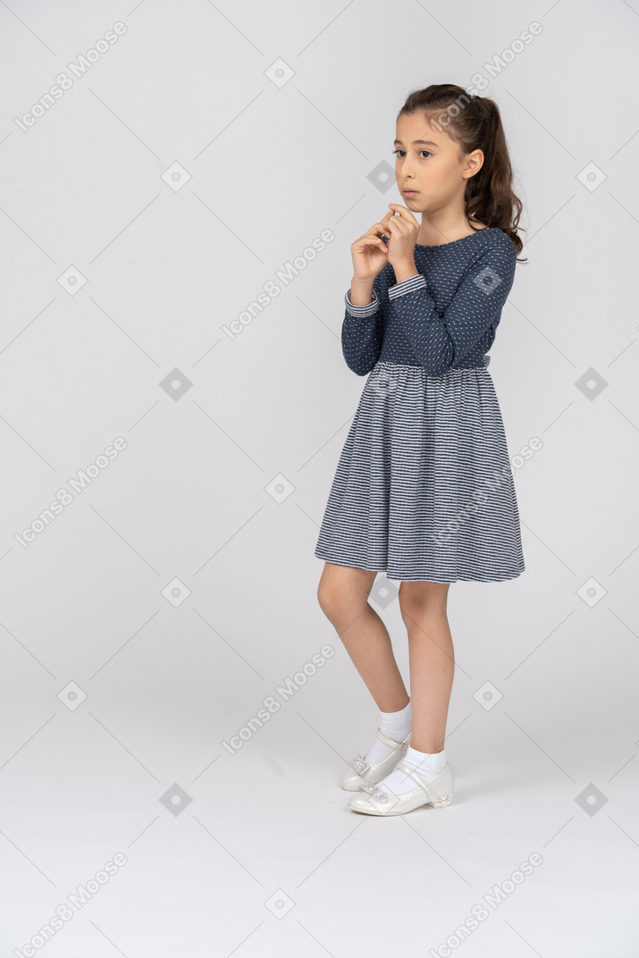 Three-quarter view of a girl holding hands to herself looking nervous