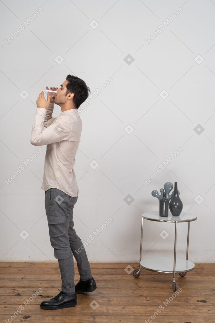 Человек в рубашке пьет воду
