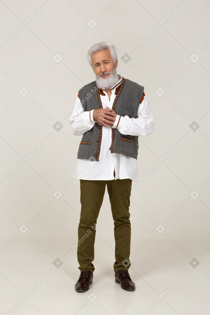 Puzzled-looking adult man standing with clasped hands