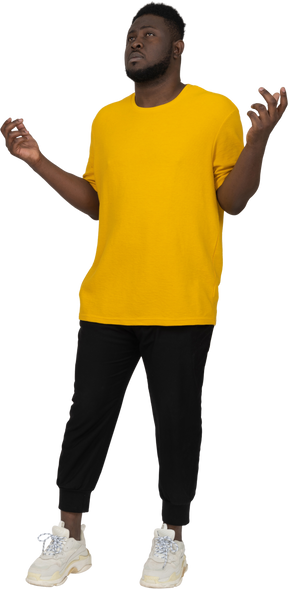 Three-quarter view of a young dark-skinned man in yellow t-shirt raising hands