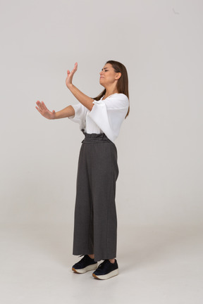 Vista lateral de una señorita reacia en ropa de oficina extendiendo el brazo