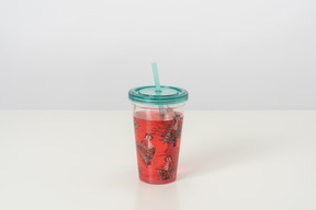 A cute plastic cup with a lid and a straw, full of pink-coloured cocktail, looking cool and aesthetically pleasing