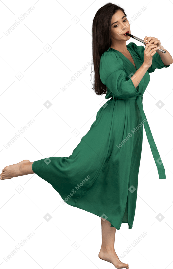 Вид сбоку на босую девушку в зеленом платье, играющую на флейте