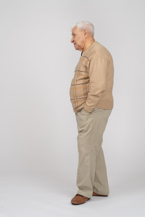 Vista lateral de um velho em roupas casuais em pé com as mãos nos bolsos