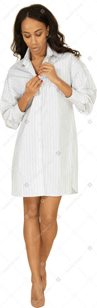 一个扣紧她的白色连衣裙的深色皮肤的年轻女性的前视图
