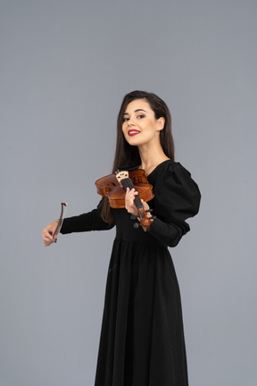 Close-up of a smiling young lady in black dress playing the violin