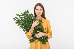 Jeune femme tenant le bouquet de branches vertes