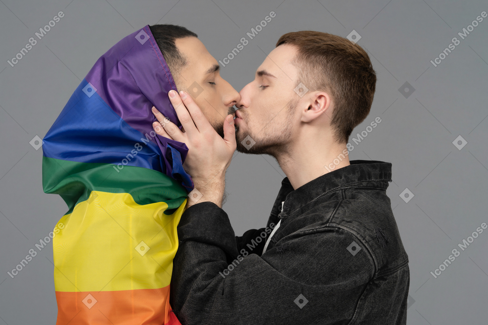 Close-up of young man kissing another man wrapped in lgbt flag