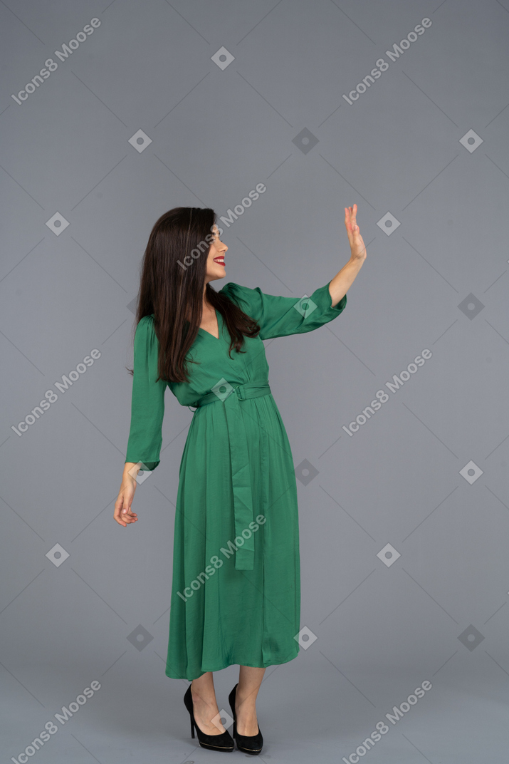 Three-quarter view of a greeting young lady in green dress