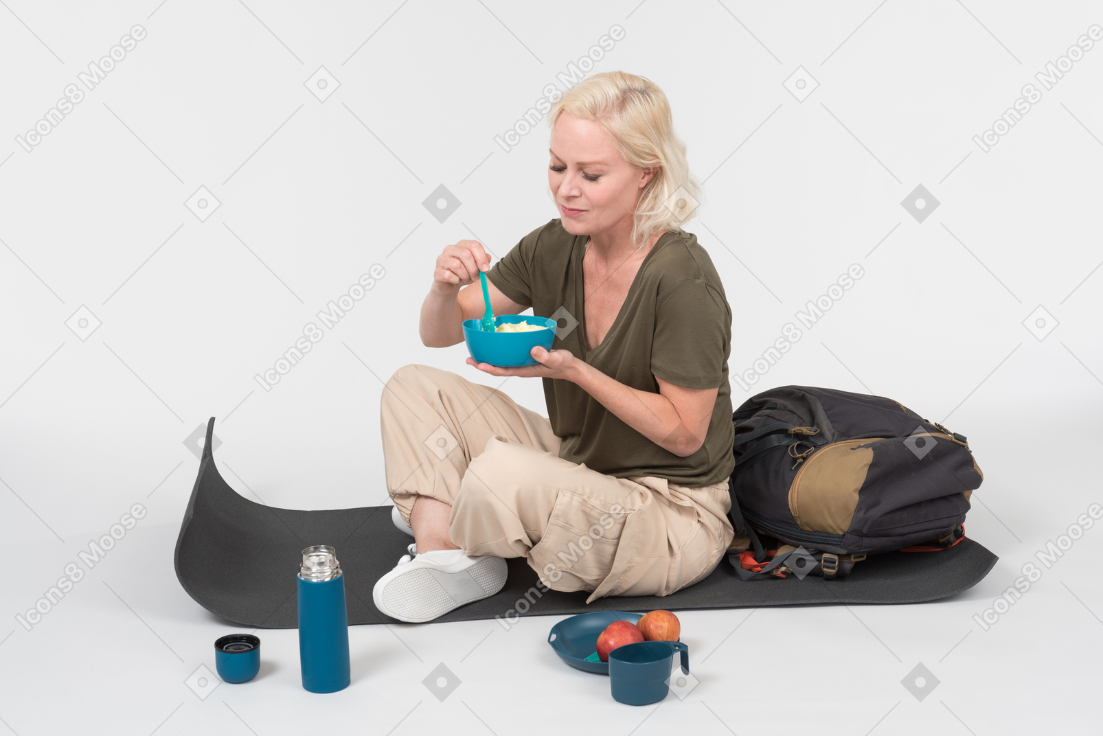 Mature female tourist sitting on tourist mat and eating