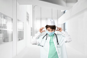 Little boy doctor puting on a face mask in a hospital