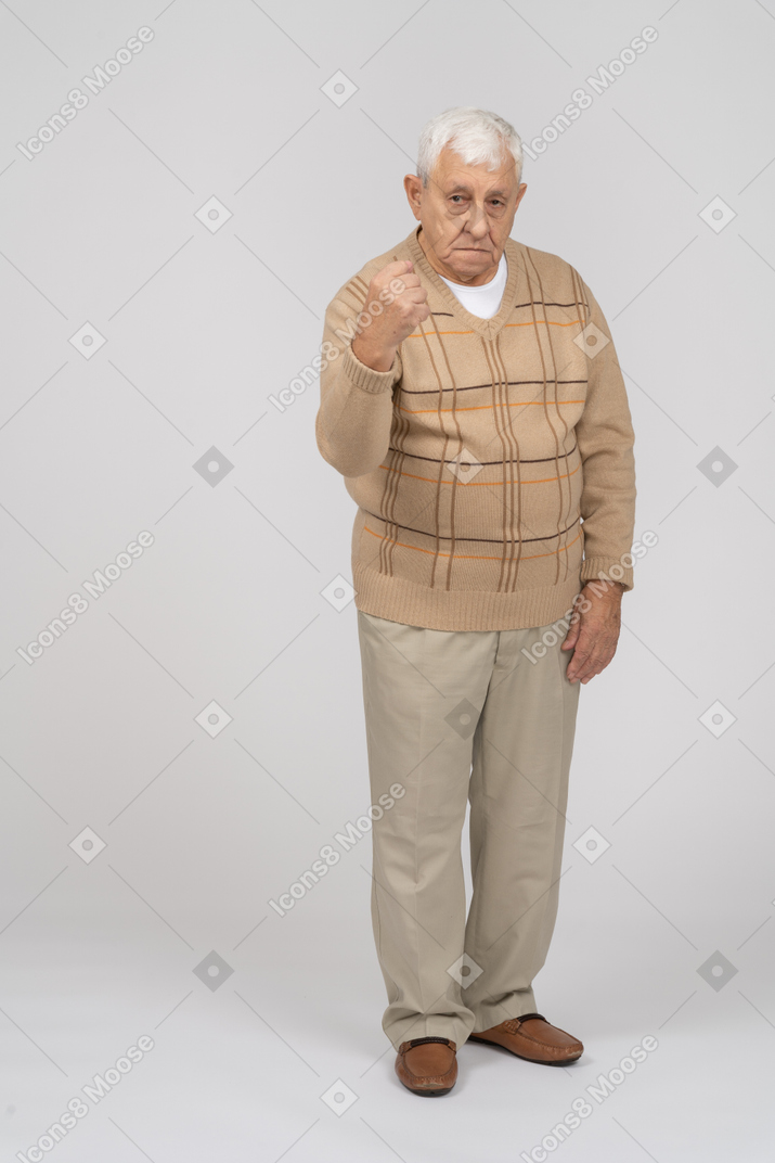 Vista frontal de um velho zangado em roupas casuais, mostrando o punho