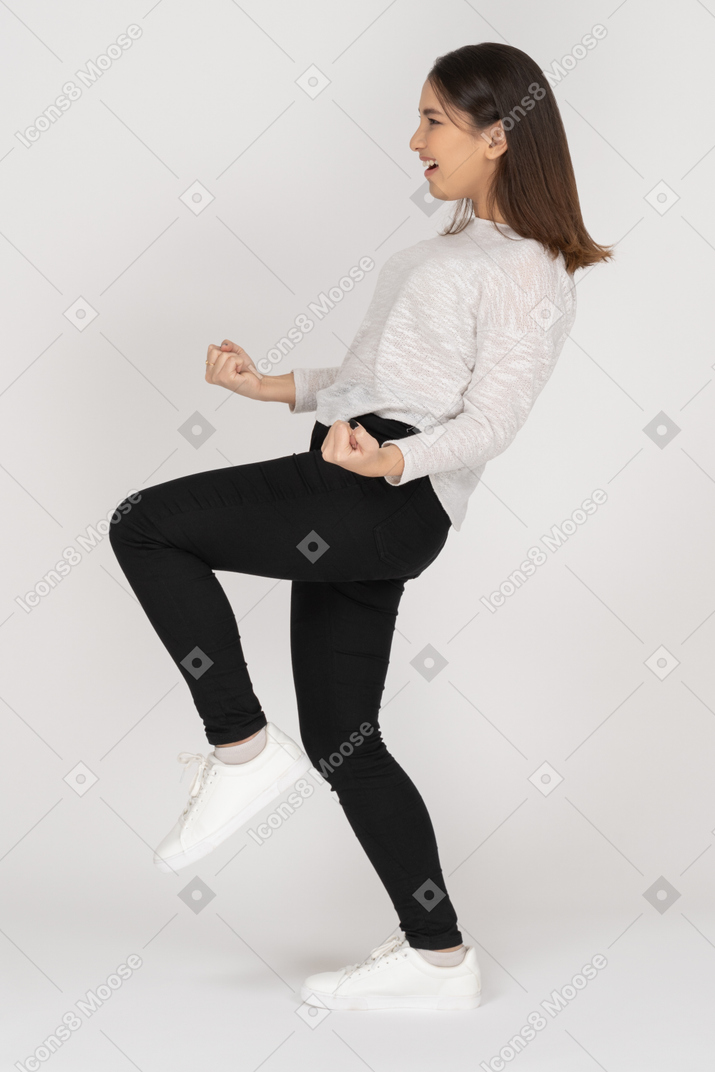 Side view of a happy young indian female in casual clothing clenching fists