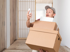 Delivery man carrying cardboard boxes and looking at a smartphone