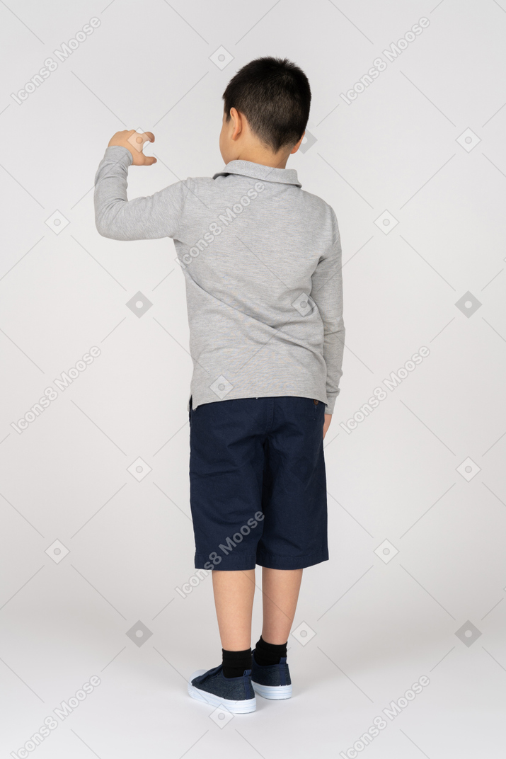Rear view of a boy measuring something small