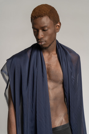Vista frontal de um jovem afro olhando para baixo com um xale sobre os ombros