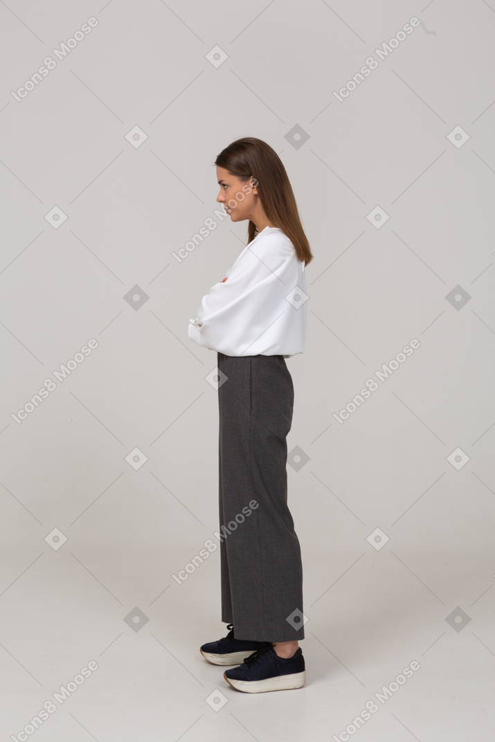 一位身着办公室服装的严肃年轻女士交叉双臂，望向一边的侧视图