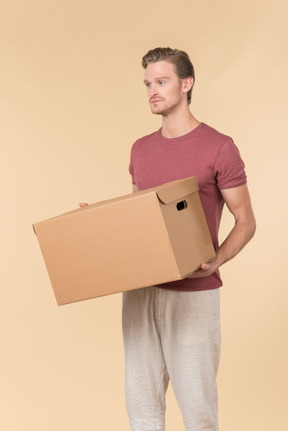 Delivery guy standing half sideways and holding parcel