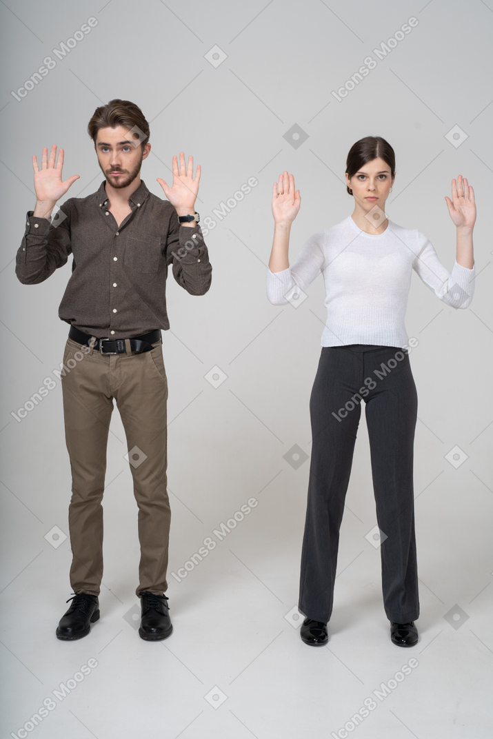 手を上げて事務服を着た若いカップルの正面図